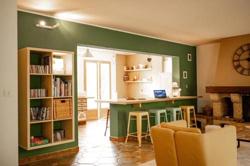 une cuisine aux murs verts et un bar avec tabourets dans l'établissement La maison du Diplo : Forêt, sentiers et grimpe, à Le Vaudoué