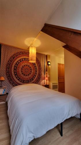 a bedroom with a large white bed with a wall at La maison du Diplo : Forêt, sentiers et grimpe in Le Vaudoué