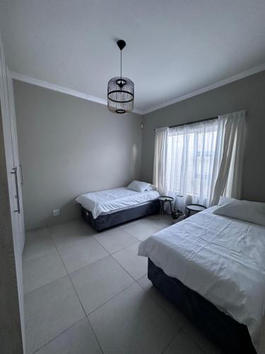 una camera con due letti e una finestra con un lampadario a braccio di Cozy Home Self-Catering a Walvis Bay