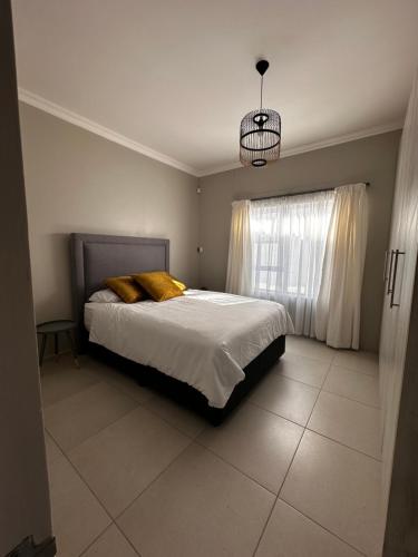 una camera da letto con un letto con cuscini gialli e una finestra di Cozy Home Self-Catering a Walvis Bay