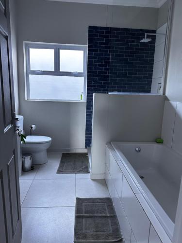 baño con bañera, aseo y ventana en Cozy Home Self-Catering, en Walvis Bay