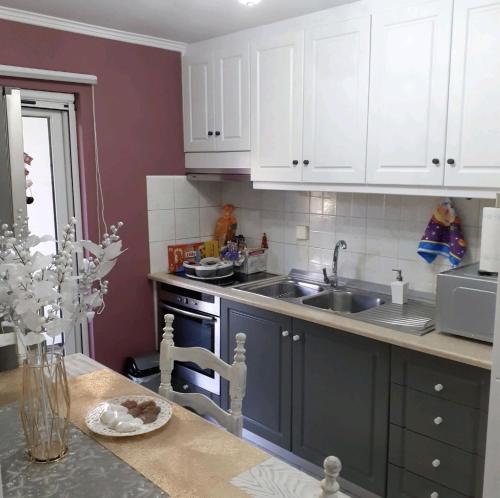 a kitchen with white cabinets and a sink at DreamHouse in Nafpaktos