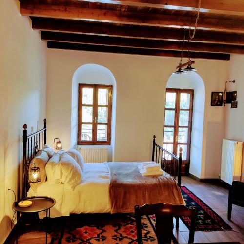1 dormitorio con 1 cama grande y 2 ventanas en Kristi's Homes - ''Traditional Home'' in Dimitsana, en Dhimitsana