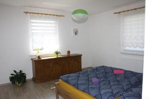 a bedroom with a bed and a dresser and two windows at Šumava U Janiny in Strážov