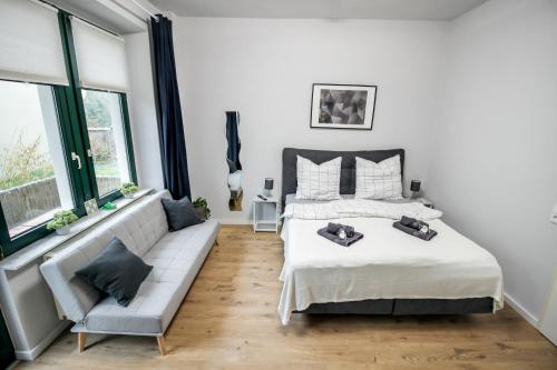 ein Schlafzimmer mit einem Bett, einem Sofa und Fenstern in der Unterkunft Ferienwohnung Lorenz mit kostenlosem Parkplatz Netflix Boxspringbett Küche in Magdeburg