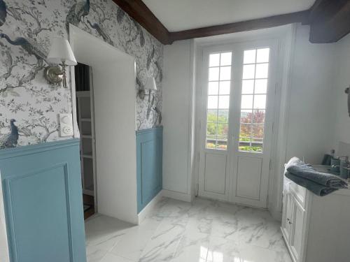 a white hallway with a door and a window at Le Manoir de Sainte-Aulde in Sainte-Aulde