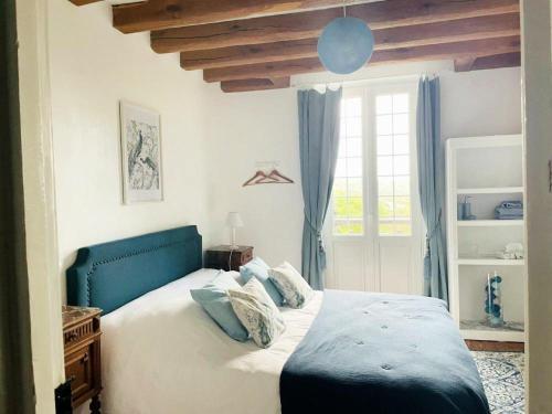 a bedroom with a bed with a blue headboard and a window at Le Manoir de Sainte-Aulde 