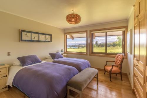 a bedroom with two beds and a chair and a window at B&B Puerto Varas Playa Venado in Puerto Varas