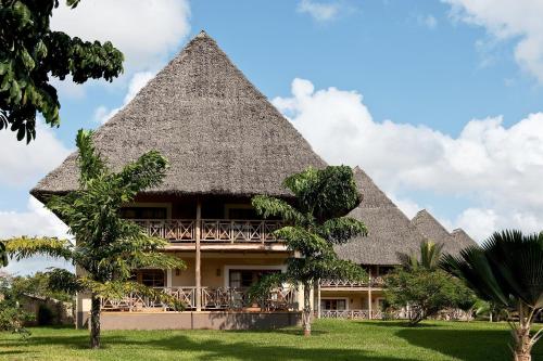a resort building with a thatched roof at Neptune Palm Beach Boutique Resort & Spa - All Inclusive in Galu