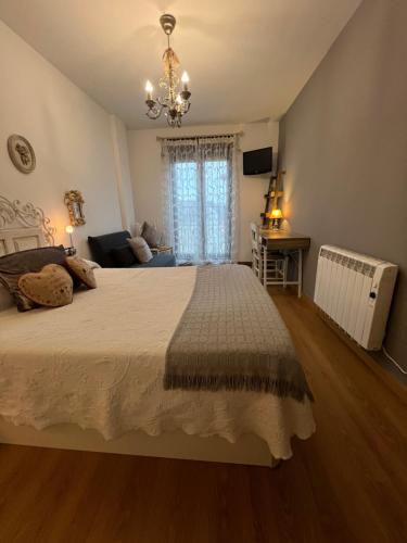 a bedroom with a large bed and a chandelier at A. Rural LA COVATILLA en Navacarros in Navacarros