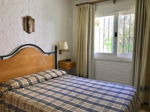 a bedroom with a bed with a plaid blanket and a window at Casa de 6 ambientes a 2 cuadras de la playa brava in Punta del Este