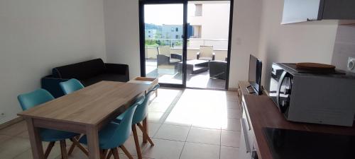 une cuisine avec une table en bois et des chaises bleues dans l'établissement Grand T2 neuf classé 3 étoiles, à Porticcio