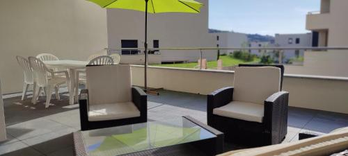 un balcon avec une table, des chaises et un parasol dans l'établissement Grand T2 neuf classé 3 étoiles, à Porticcio