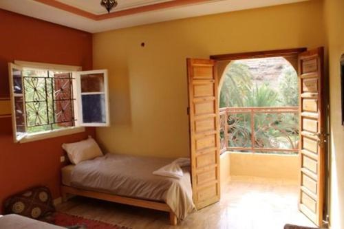 a bedroom with a small bed and an open window at Gite TALBOURINE in Taroudant