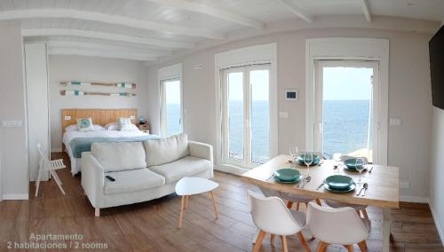 Vila Mariña. Casa marinera con terraza sobre el mar en Caión في Cayón: غرفة معيشة مع أريكة وطاولة وسرير