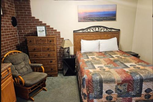 a bedroom with a bed and a chair at Riverbank Motel and Cabins Managed by Vacasa in Lincoln