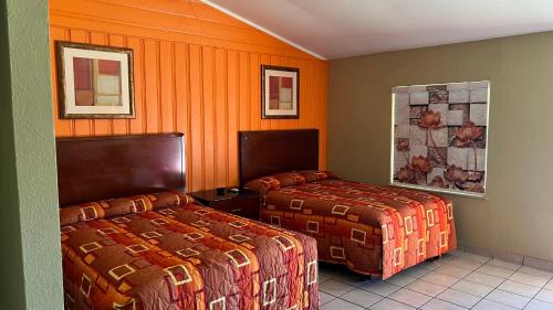 two beds in a hotel room with orange walls at Budget Inn Greenville in Greenville