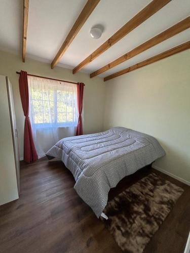 ein Schlafzimmer mit einem Bett in einem Zimmer mit einem Fenster in der Unterkunft Cabañas Vista Volcanes II in Puerto Varas