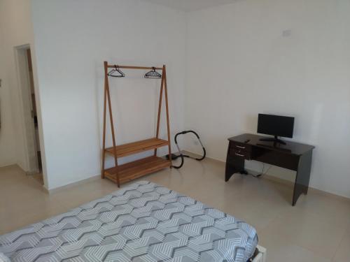 ein Schlafzimmer mit einem Bett und einem Schreibtisch mit einem Monitor in der Unterkunft Casa ampla com fácil acesso as Praias e Shopping in Caraguatatuba