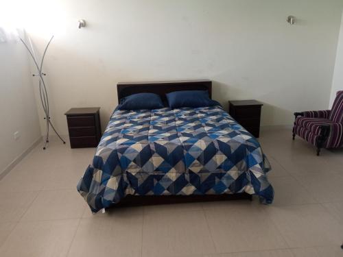 Un dormitorio con una cama azul y blanca y una silla en Casa Villa Eru, en Gallinazos Hacienda