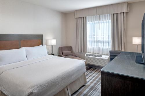 a hotel room with a bed and a chair and a window at Fairfield Inn & Suites by Marriott Airdrie in Airdrie