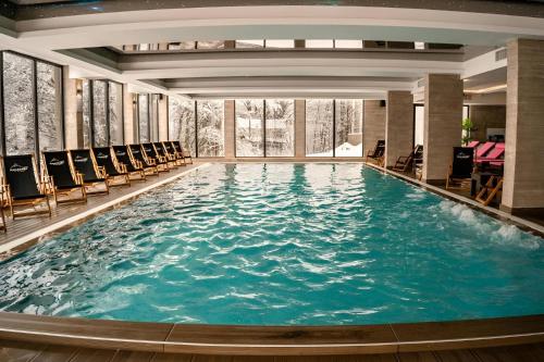 a large swimming pool in a hotel with chairs at NLux 10 Apartment in Kopaonik