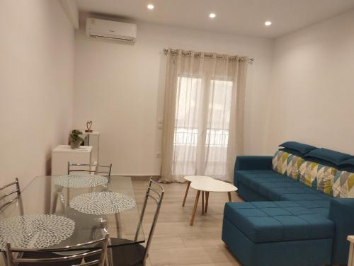 PortoHeli Matilda`s house 2 في بورتوخيلي: غرفة معيشة مع أريكة زرقاء وطاولة