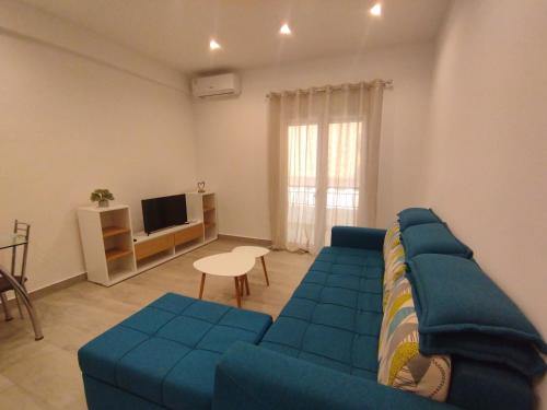 uma sala de estar com um sofá azul e uma televisão em PortoHeli Matilda`s house 2 em Porto Heli