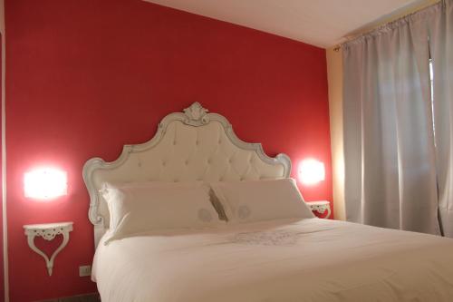 1 dormitorio con cama blanca y pared roja en Villa Giuly, en Antronapiana