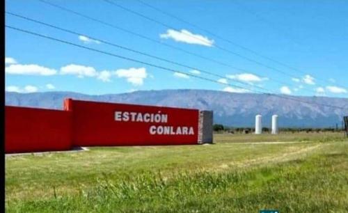 a red building in a field with mountains in the background at Cabaña Dina in Santa Rosa del Conlara