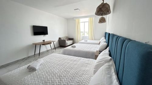 a white room with two beds and a tv at Hotel Presidente Beach Playas in Playas