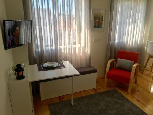 a living room with a table and a red chair at Studio Jardim São Lázaro in Porto