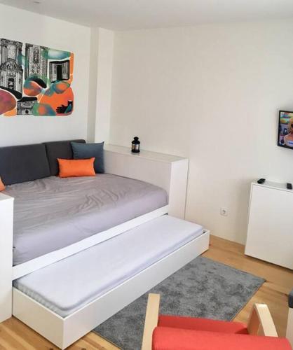 a bedroom with a white bed with an orange pillow at Studio Jardim São Lázaro in Porto