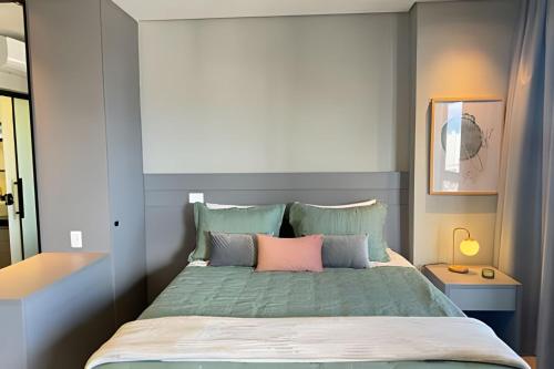 sypialnia z łóżkiem z różowymi i zielonymi poduszkami w obiekcie Vertigo 243 - Gestão FGibran. w mieście Campo Grande