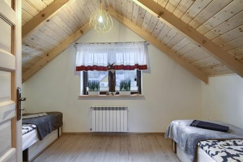 a attic bedroom with two beds and a window at Domek Jaśkowy w Tyliczu in Tylicz