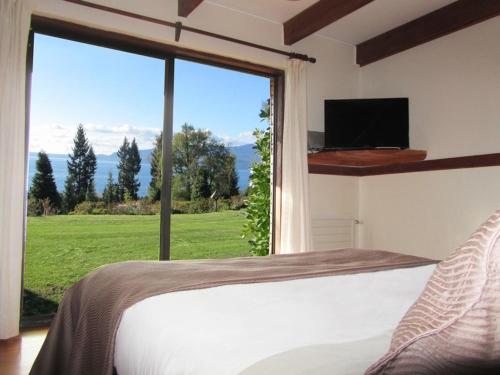 ein Schlafzimmer mit einem Bett und einem großen Fenster in der Unterkunft Cabañas Portal Pucon in Pucón