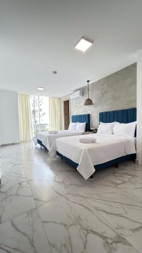 two beds in a large bedroom with marble floors at Hotel Presidente Beach Playas in Playas