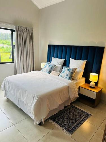 a bedroom with a large bed with a blue headboard at Ekhaya Luxury Apartment in Lobamba