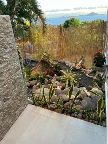 a garden with plants and rocks and a fence at Villa Cajou chambres d'hôtes chez l'habitant et Zanzibar cottage in Trois-Rivières