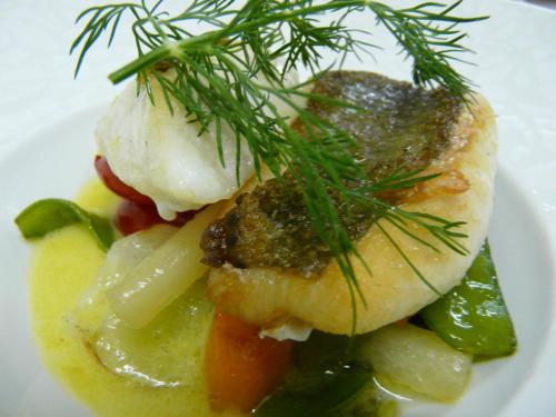 a plate of food with a piece of fish and vegetables at Hostellerie d'Héloïse Logis in Cluny
