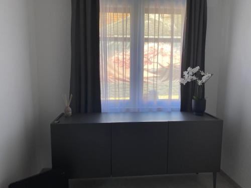 a black dresser in a room with a window at Shubu GARDEN Vendégházak in Szilvásvárad