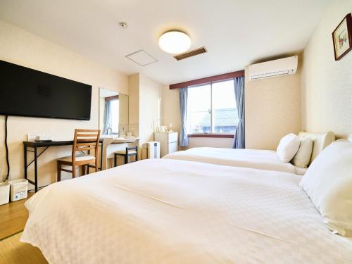 a hotel room with two white beds and a desk at Okasan Hotel - Vacation STAY 45150v in Ogaki