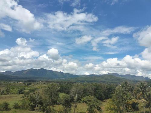an open field with mountains and a blue sky with clouds at Evergreen Shola View in Chikmagalūr