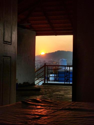 a view of the sunset from a building with a balcony at Evergreen Shola View in Chikmagalūr