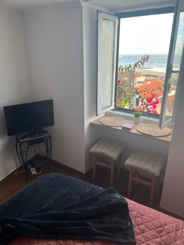a bedroom with a bed and a television and a window at Alfama authentic Lisbon in Lisbon