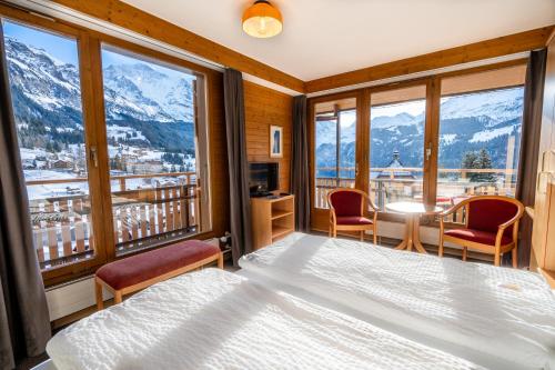 a bedroom with a bed and a balcony with mountains at Hotel Jungfraublick in Wengen