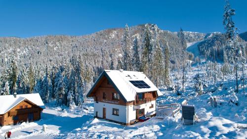 a house covered in snow with a mountain in the background at Villa pod hviezdami Jasná in Demanovska Dolina