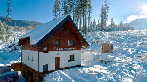 una piccola casa ricoperta di neve in un campo di Villa pod hviezdami Jasná a Demänovská Dolina