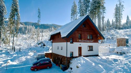 una pequeña casa con un coche rojo aparcado en la nieve en Villa pod hviezdami Jasná, en Demänovská Dolina
