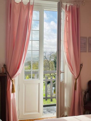 a bedroom with a window with pink curtains at Le Manoir de Sainte-Aulde in Sainte-Aulde